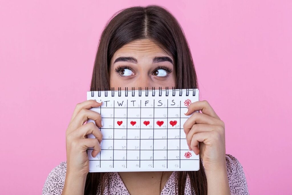 Mulher segurando um calendário menstrual, observando o ciclo para identificar os primeiros sinais de gravidez e possíveis atrasos.