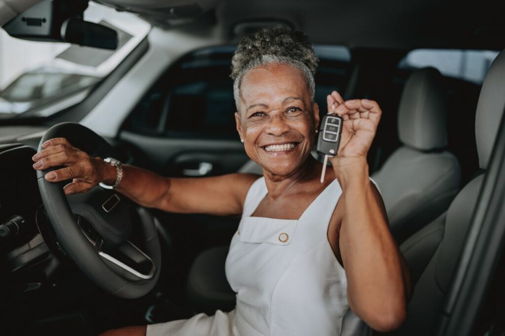 Mulher sorridente dentro do carro segurando a chave do veículo, simbolizando a satisfação e segurança após consultar informações do veículo de forma simples e confiável