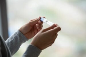 Pessoa segurando um teste de gravidez para identificar os primeiros sinais de gravidez e confirmar a gestação com segurança.