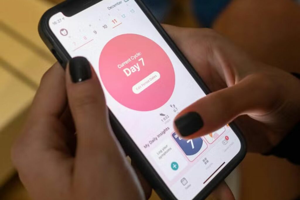 Pessoa utilizando o aplicativo Flo App no celular para acompanhar o ciclo menstrual e identificar sintomas da gravidez de forma prática e precisa.
