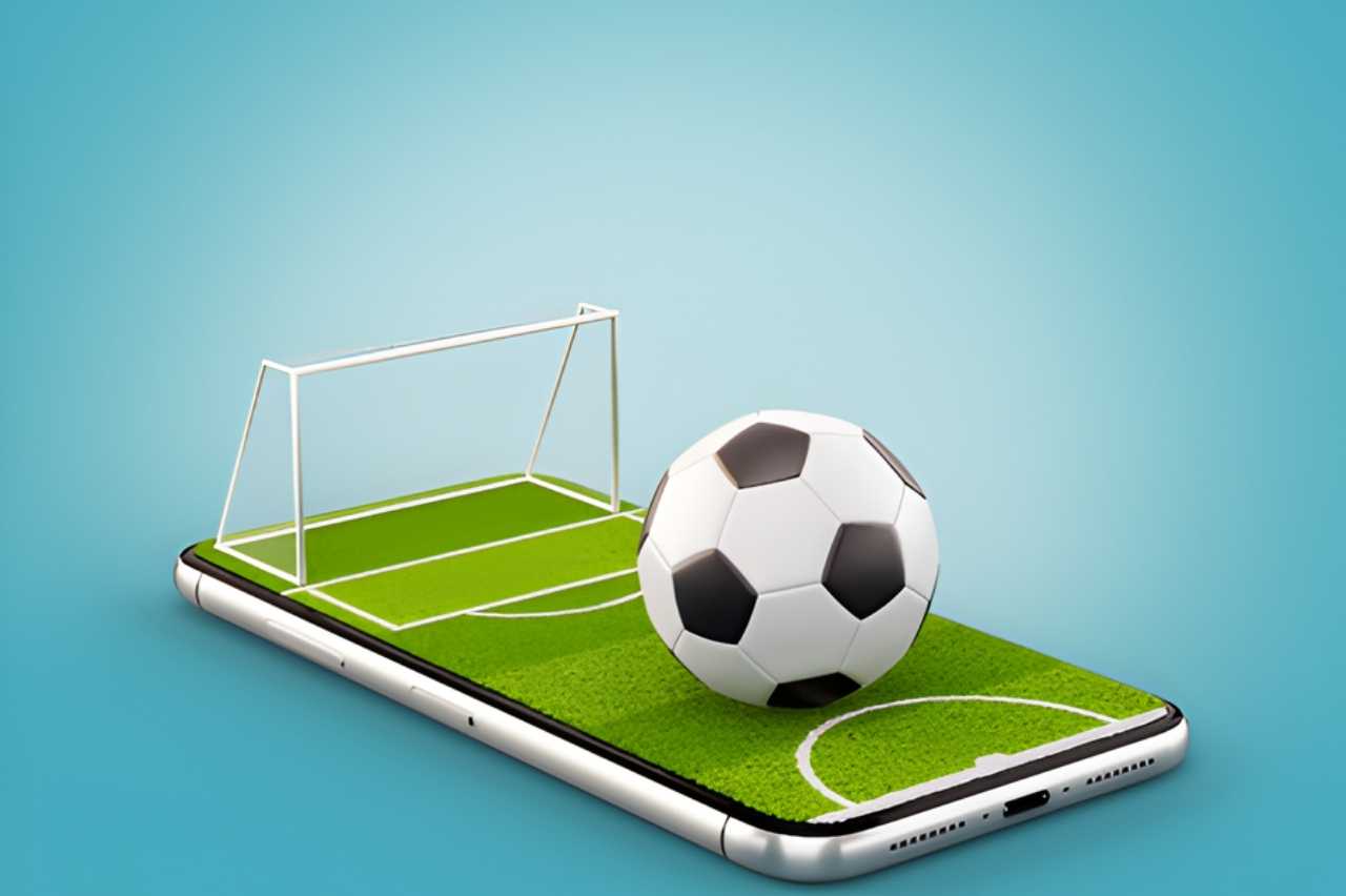 Bola de futebol e gol em miniatura sobre smartphone, representando aplicativos para assistir futebol ao vivo pelo celular com praticidade e acesso em tempo real.